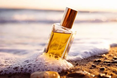 Close up of rectangular glass bottle with golden perfume washed by sea surf,  Foto stock