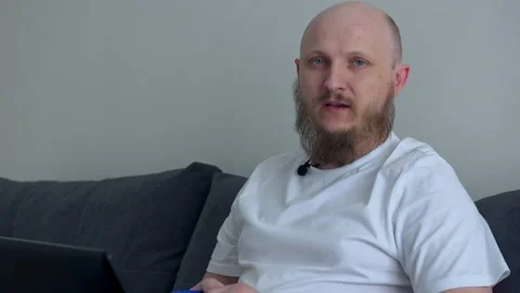 Close-up of the rector sitting on the couch at home and telling the teaching Stock Footage 201311202