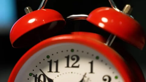 Close-up of a red alarm clock with a classic design, featuring two bells on.. Stock Footage 321936943