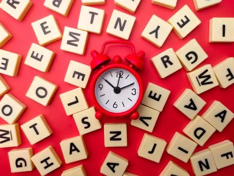 Close-up of a red alarm clock surrounded by a collage of colorful blocks with di Stock Photos