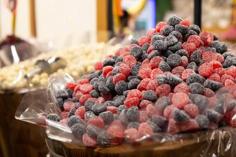 Close up of red and black candy in container in candy shop. Stock Photos