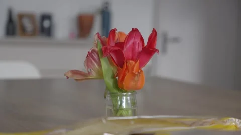 Close-up of red and orange tulips in a glass vase on a wooden table. Bright Видео 335347502