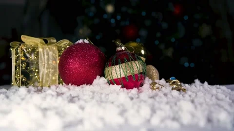 Close up of Red bobbles and parcel on white snow with Chritmas tree lights Stock Footage 143804801