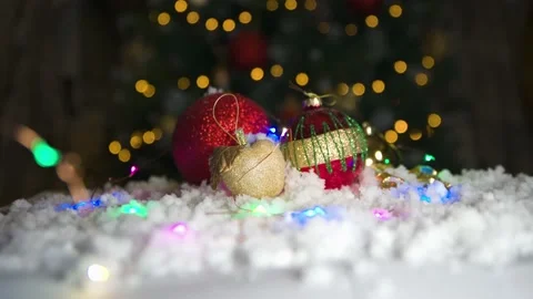 Close up of Red bobbles and parcel on white snow with Chritmas tree lights Stock Footage 143806713