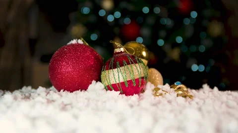 Close up of Red bobbles on white snow with Chritmas tree lights flickering in Stock Footage 143803920