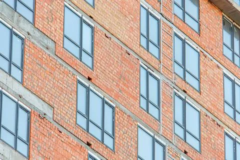 Close-up of red brick, modern construction site with window frames installed  Stock Photos