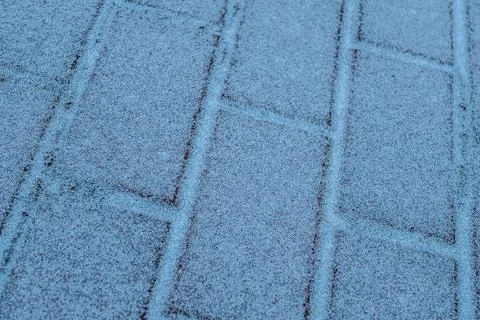 A close-up of red brick tiles lightly covered in frost or snow, creating. Fotos de archivo