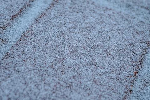 A close-up of red brick tiles lightly covered in frost or snow, creating. Fotos de archivo