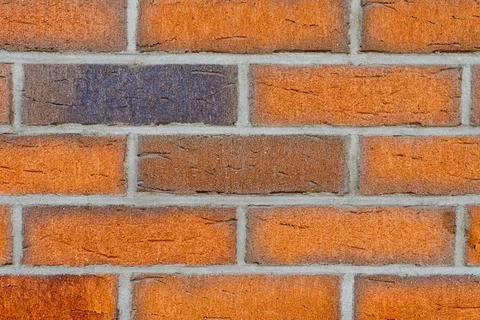 Close-up of red brick wall with one darker brick among red bricks 스톡 사진