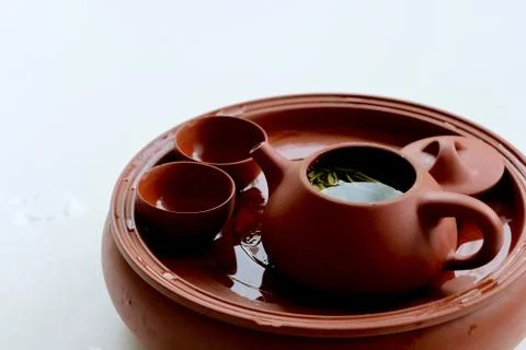 Close up red brown ceramic clay fired teapot and teacups on white background Stock Photos