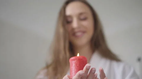 Close-up red burning candle in slim female hand with blurred Caucasian brunette Stock Footage 161255331