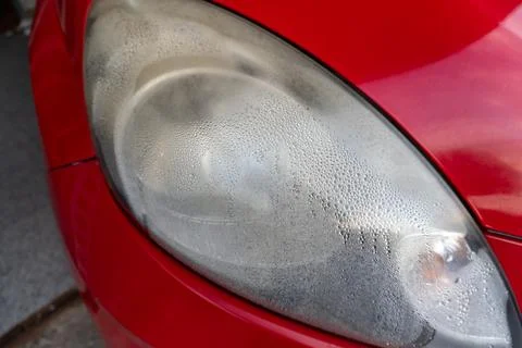 Close up of red car headlight covered with water condensation and fog 库存照片