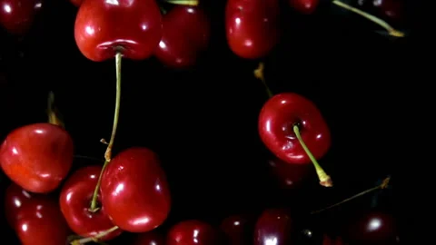 Close-up of red cherries flying up and rotating on a black background Stock Footage 138014078