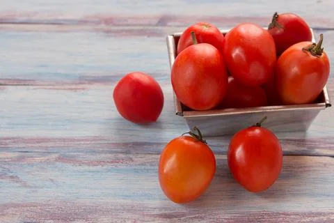 Close up red cherry plum tomatoes in stainless bowl on wood table background Stock Photos