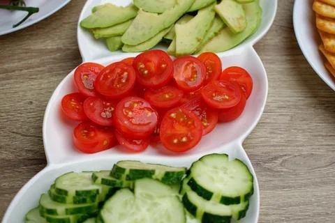 Close-up of red cherry tomatoes sliced on a white plate. Stock Photos
