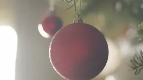 Close Up of Red Christmas Bauble Hanging on Xmas Tree with Sun Haze Lighting as Stock Footage 323805256