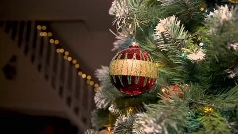 Close up of Red christmas bobble on tree with home living room stairs in Video stock 144391556