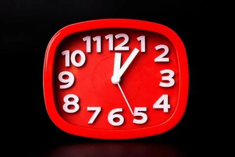 Close-up of red clock time lapse on black background. A red wall clock runn.. Stock Illustration