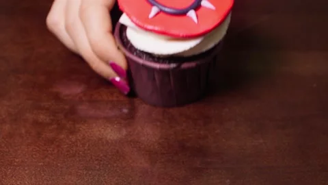 Close up of red cupcake appearing in shot. Woman hand pushes a red dessert Stock Footage 155533390
