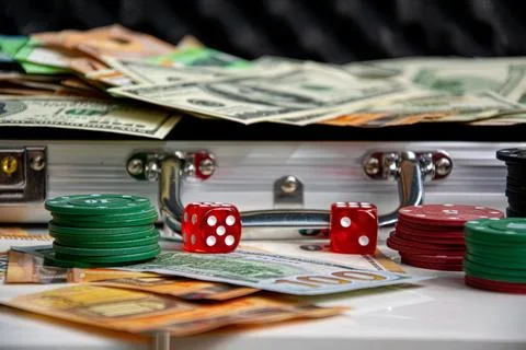 Close-up of red dice and stacks of poker chips on a white surface. A silver s Stock Photos