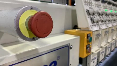 Close-up of red emergency stop button on industrial embroidery machine Stock Photos