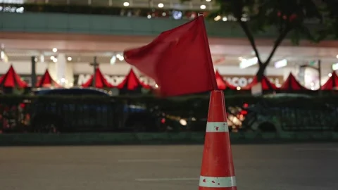 Close-up of a red flag mounted on an orange traffic cone placed on the city Video stock 310164123