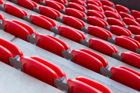 Close up of red folded up seats from behind in football stadium Stock Photos