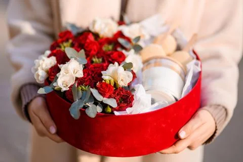 Close-up of a red gift box with a composition of roses along with a candle and Foto stock