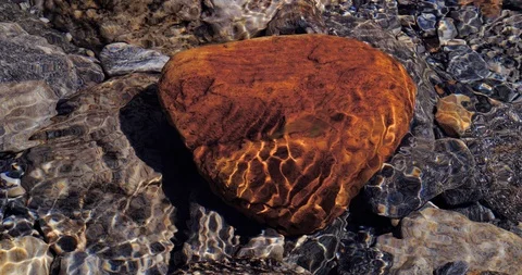 Close up of a red golden stone in the river with sunbeam reflecting Stock Footage 115077221