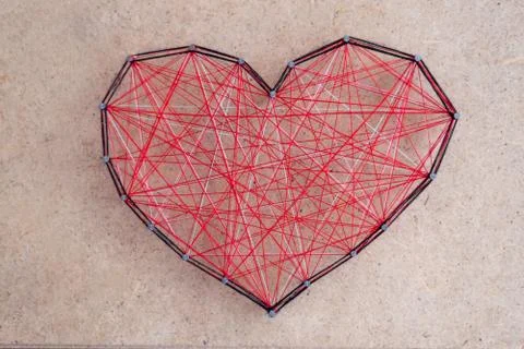 Close up of a red heart made of threads wound between nails. Stock Photos