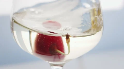 Close up of red juicy cherry flotaing in a wine cocktail transparent glass Video stock 147344939