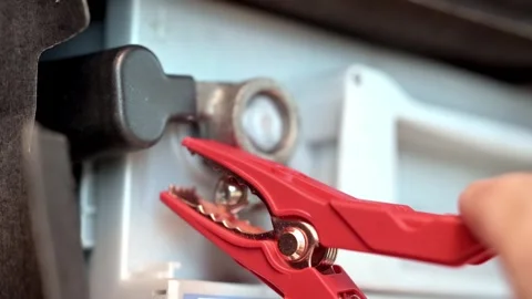 Close-Up of Red Jumper Cable Clamp Attached to Car Battery Terminal During Start Stock Footage 331902071