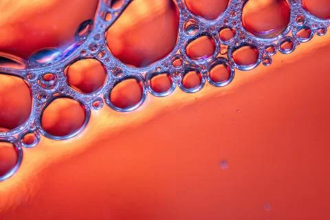 Close-up of red liquid with bubbles, showing iridescent colors and light refr Stock Photos
