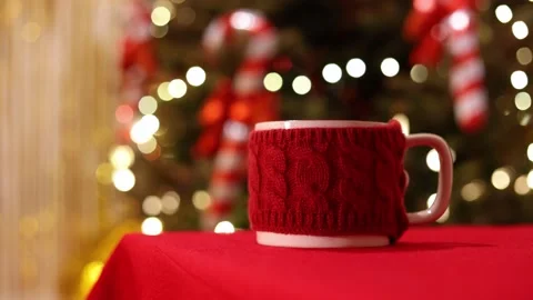 A Close Up Of A Red Mug With Knit Sweater On Holiday Table Stock Footage 313708747