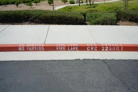 Close-up of red painted curb with Fire Lane text. Stock Photos