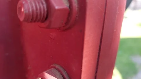 Close up of a red painted hexagon nut screwed onto a threaded bolt Stock Footage 336008107