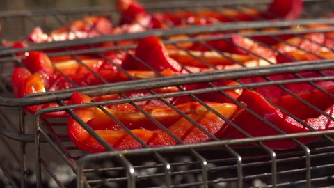 Close-up of red pepper slices in stainless mesh grill, light smoke, spring light Stock Footage 332558830