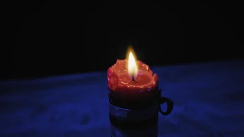Close Up Red Pillar Candle Burning With Flickering Flame In Dark Blue Room Stock Footage 327715582