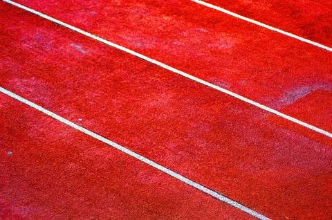 Close up of red running track with white lane lines, textured surface ideal.. Stock Photos