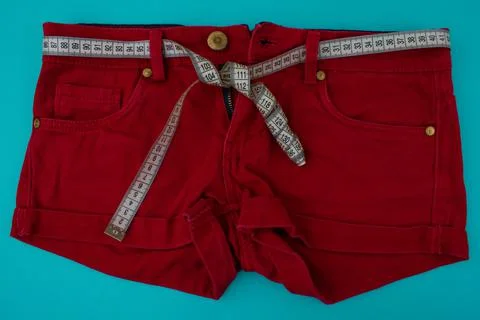 Close-up red shorts with a centimeter instead of a belt on a blue background, Stock Photos