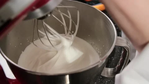 Close up of a red stand mixer which is whipping the cream in a stainless steel Stock Footage 150937120