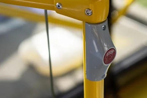 Close-up of a red STOP button mounted on a yellow pole inside a city bus. Pub Stock Photos