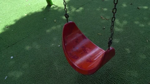 A close up of a red swing swaying at playground Stock Footage 230239559