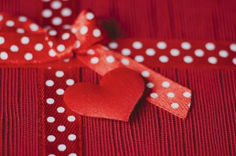 Close up of a red tiny heart and gift ribbon with white polka dots tied int.. Stock Photos