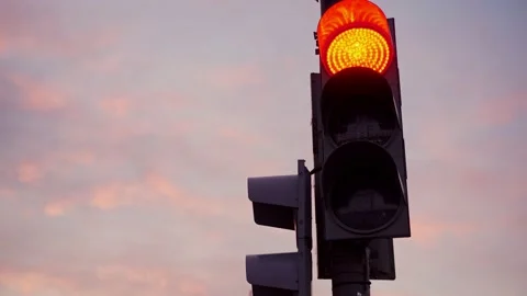 A close-up of a red traffic light turns green against a sunset sky. Stock Footage 156418278