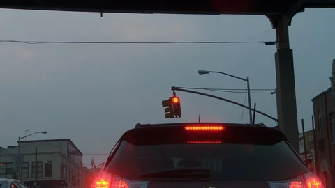 Close-up of red traffic light with vehicle brake lights on cloudy day, dusk. Vídeo Stock 108123145