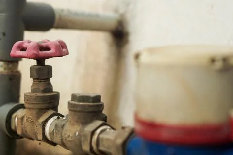 Close-up of a Red Valve Handle on Rusty Water Pipes and Meter Fotos de archivo