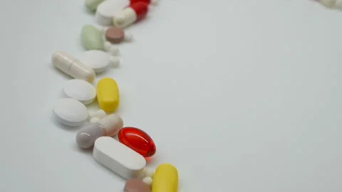 Close up, with red, white, colored pills rotating, from the left side Stock Footage 85742968
