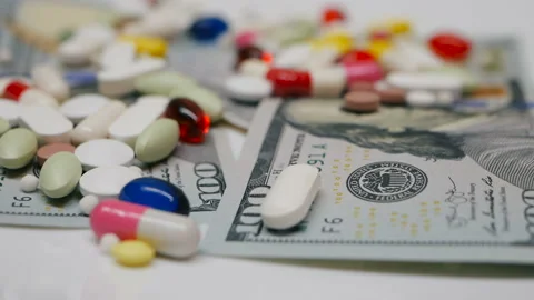 Close up, with red, white, colored pills rotating on dollars banknotes on white Stock Footage 86176925