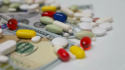 Close up, with red, white, colored pills rotating on dollars banknotes on white Stock Footage 86177004